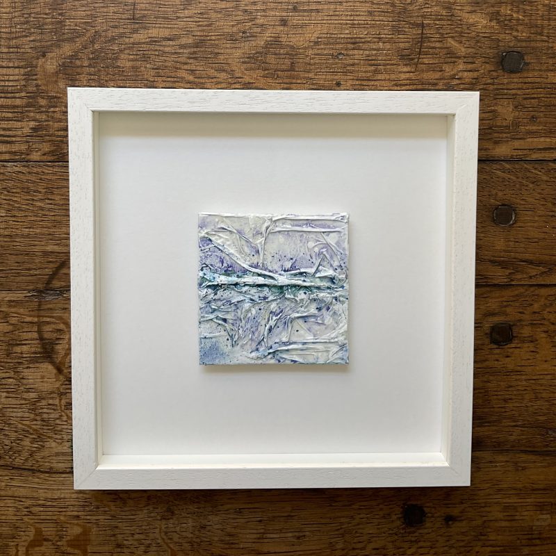 Square Mixed media blue abstract seascape, depicting the break of a wave - framed in a white wooden frame.