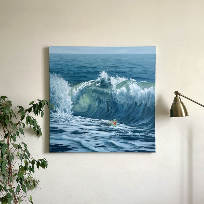 A large painting of a crashing wave hangs on the wall between a plant and a lamp in a house