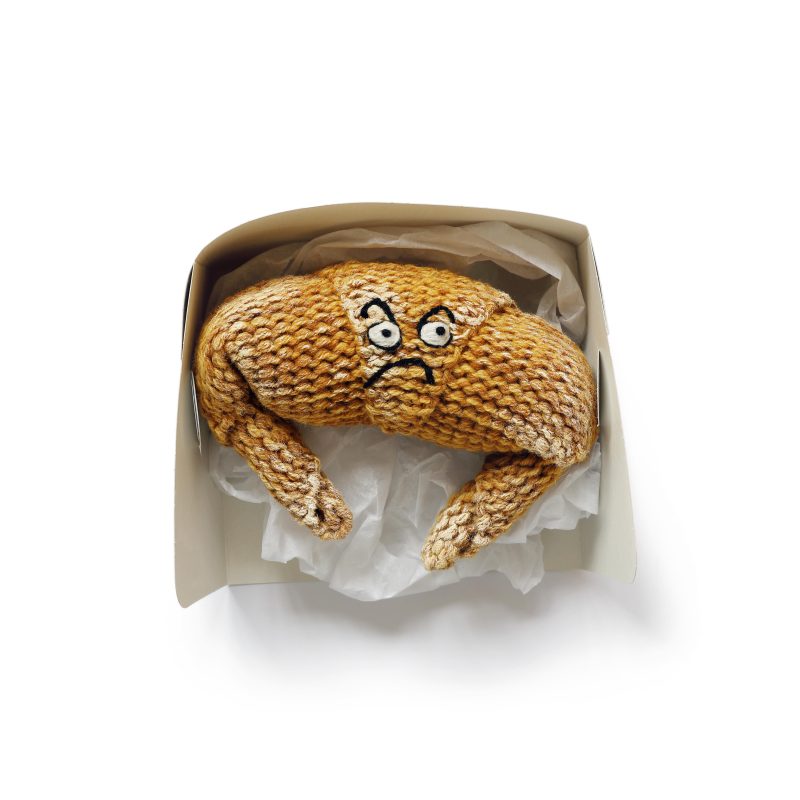 A knitted croissant with a an angry expression