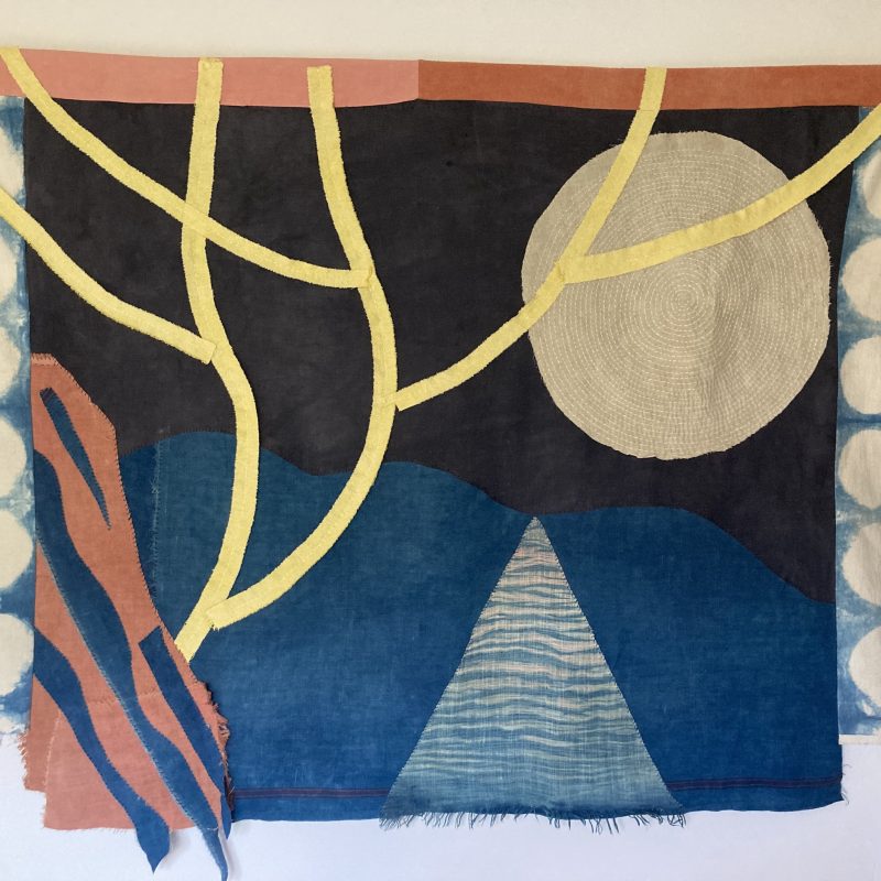 Textile Patchwork depicting a silver full moon through the branches of a yellow tree. back ground in dark indigo and blue with highlights of pink.