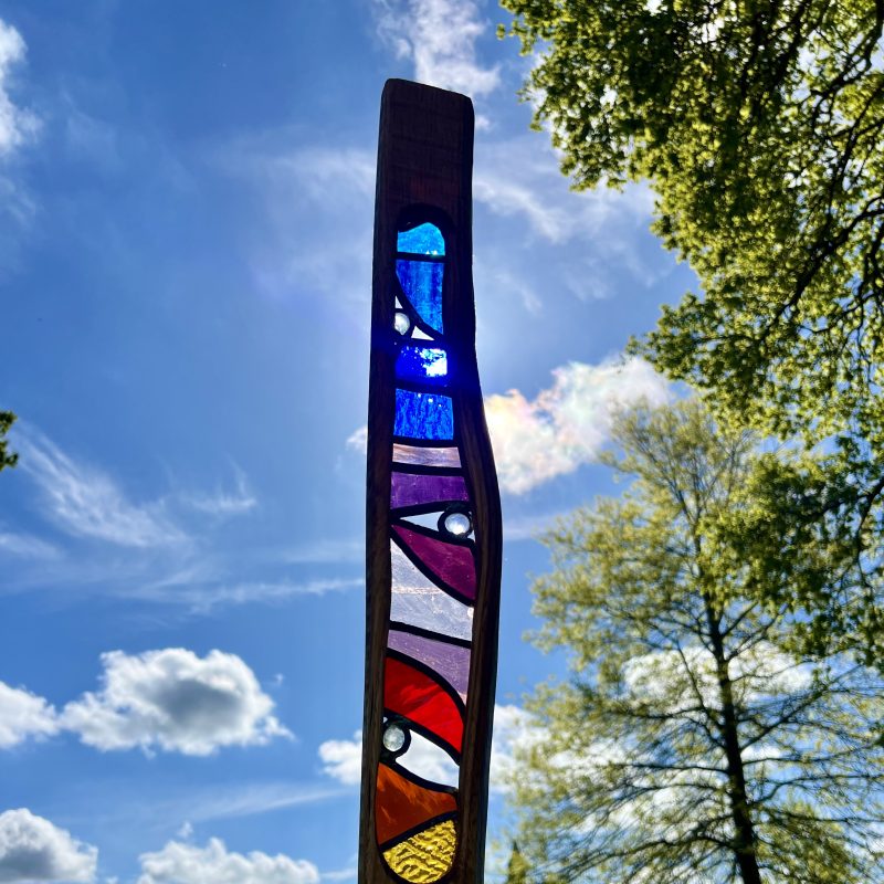 A wooden sculpture with a glass panel and against the sun