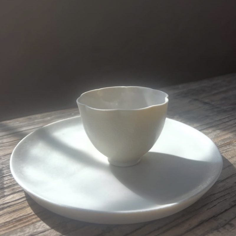 white porcelain plate and bowl sitting on a wooden surface with a dark background bathed in soft light.