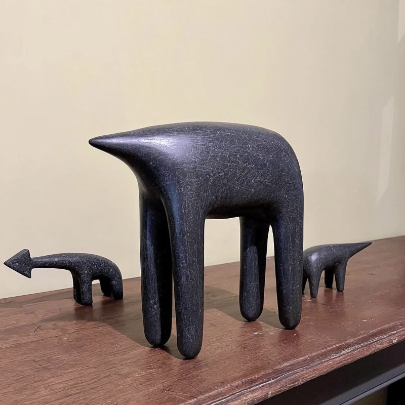 Stone Sculptures of fourlegged beast shapes on wooden table with cream background