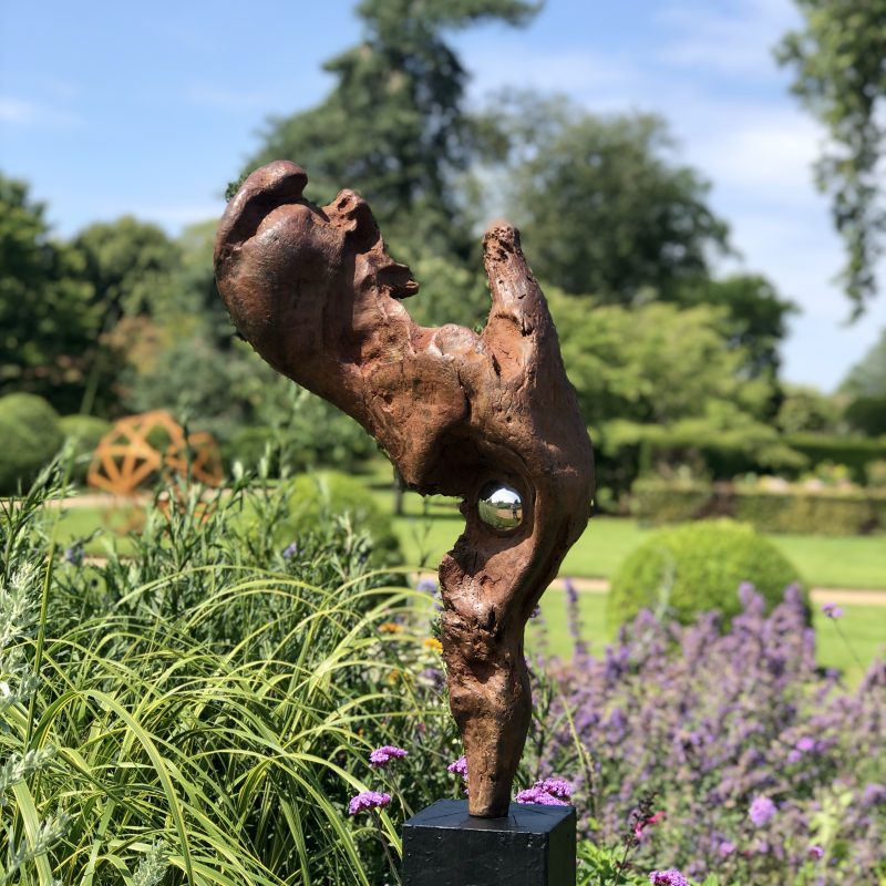 Abstract figurative sculpture with shiny silver bead nestled 