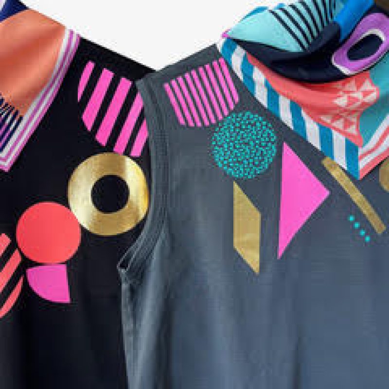 Handprinted vibrant colourful geometric shapes with gold foil detail. Placement printed stonewashed grey boxy vest top and black boxy T-shirt and geometric pattern silk scarves.