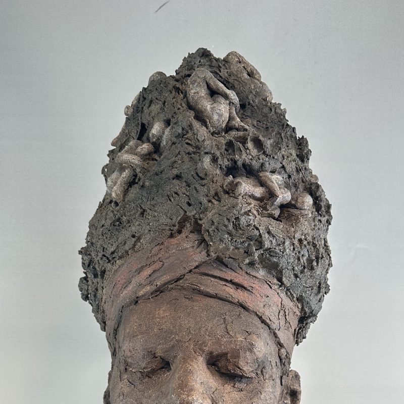 A sculpted clay head with eyes closed and a turban  